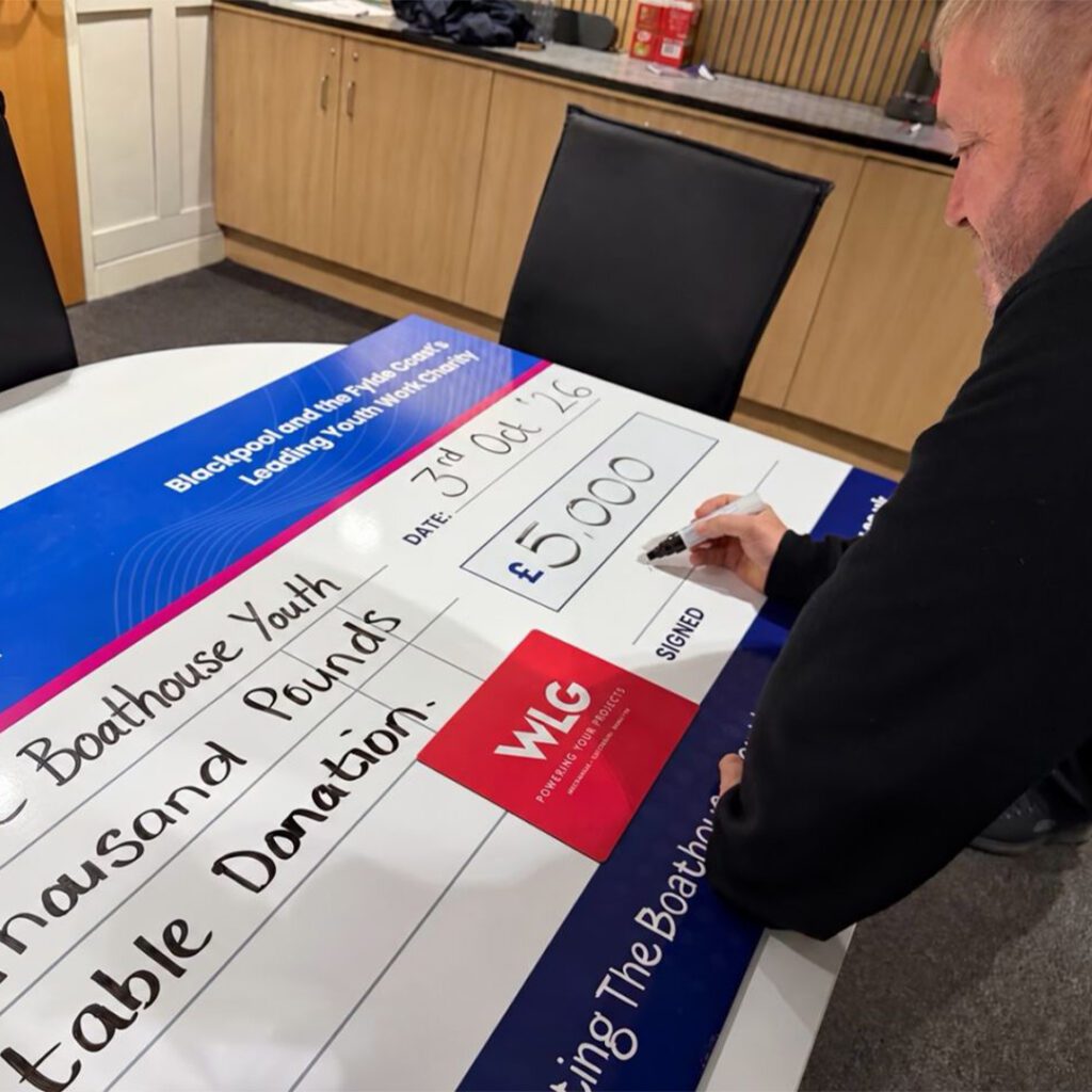 Managing Director Kevin O'Toole signing a £5,000 cheque for BKY Party Night 2026 at the WLG Offices